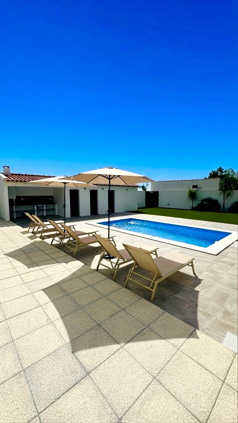 Espreguiçadeiras e chapéus de sol junto à piscina