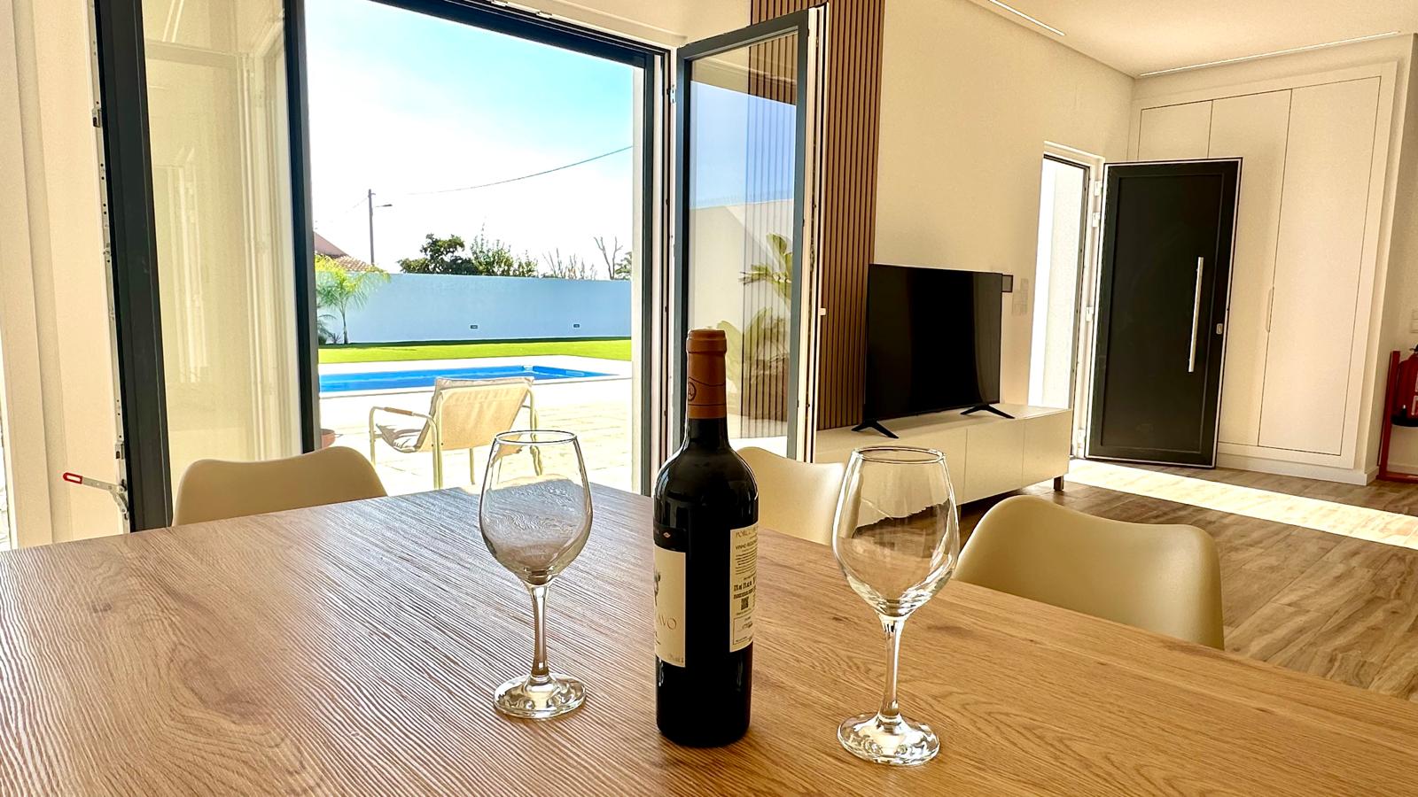 Mesa posta com garrafa de vinho e vista para a piscina