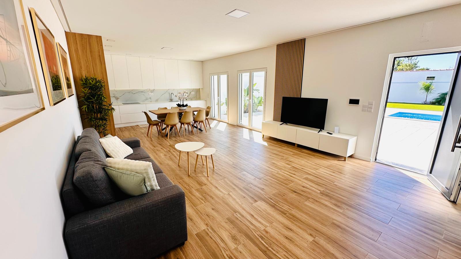 Sala de estar com vista para a cozinha e para a piscina