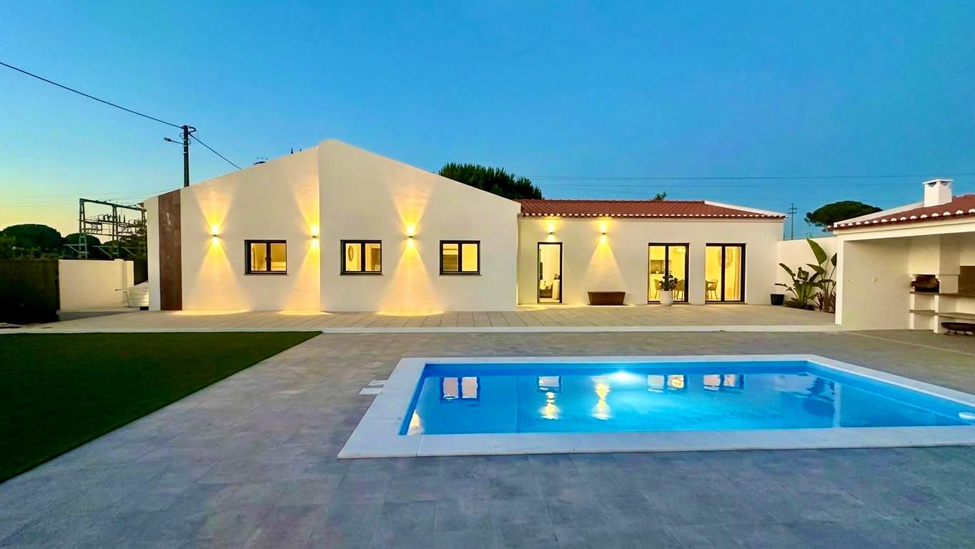 Casa do Jorge iluminada ao anoitecer, com a piscina privativa em primeiro plano